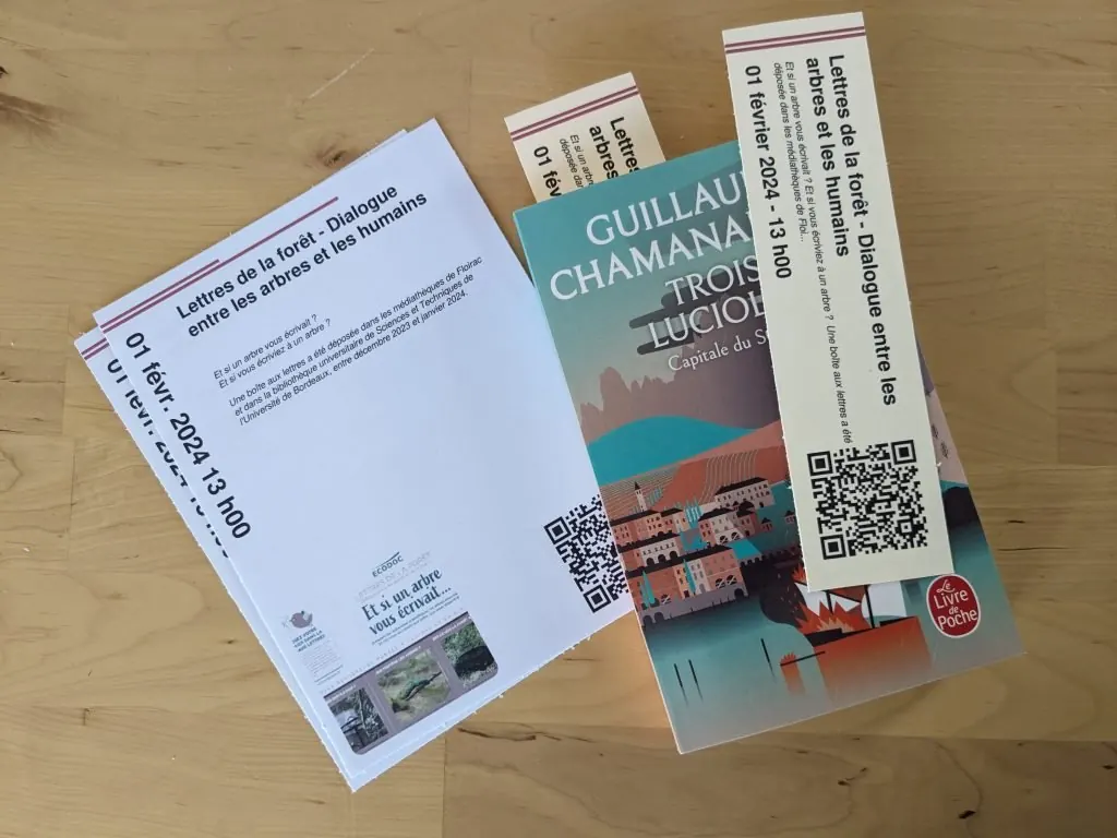 Flyers et marque-pages imprimés depuis Kronikle pour l'événement « Lettres de la forêt », chacun avec un QR code, posés sur un livre.