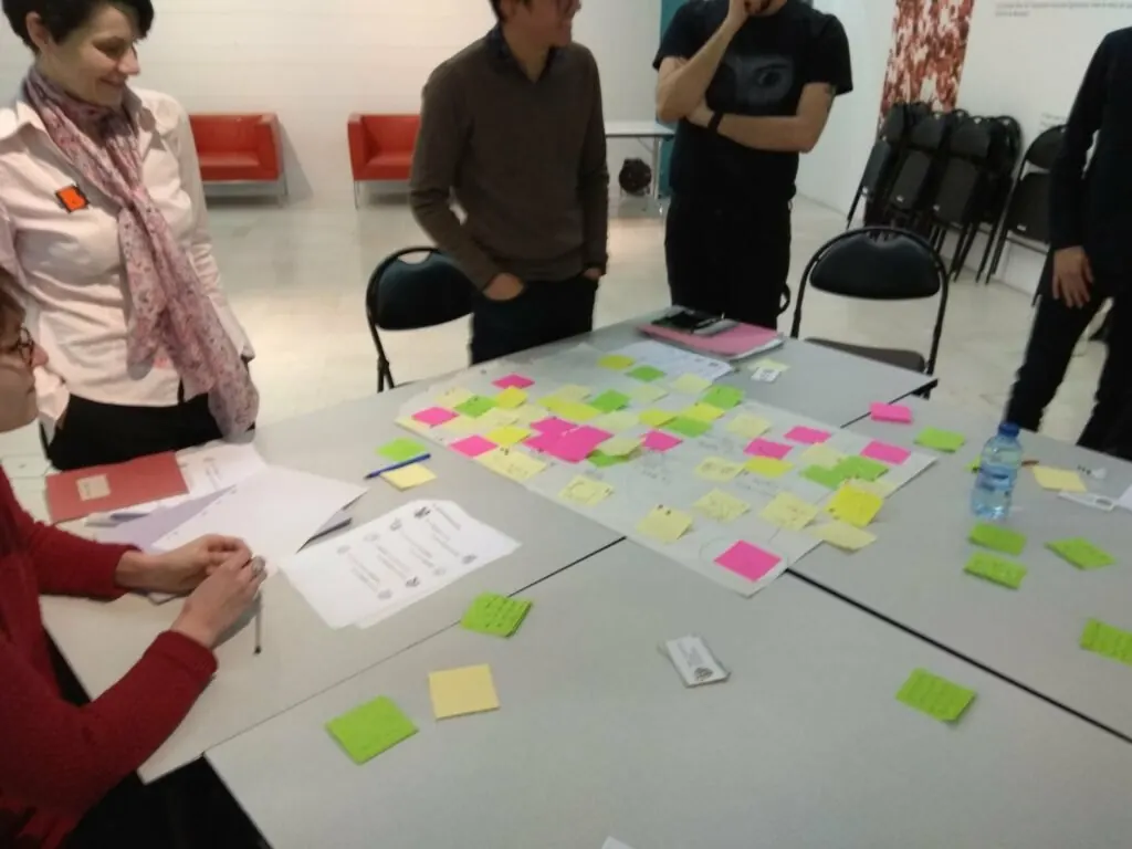 Bibliothécaires et chercheurs autour d'une table couverte de post-it pendant un atelier.